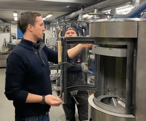 Zwei Männer arbeiten gemeinsam in einer Werkstatt an der Entwicklung eines Holzofens – wo Handwerk auf moderne Technik trifft