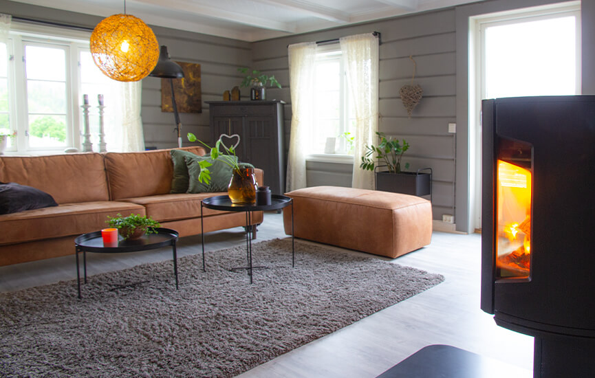 Kaminofen im grauen Wohnzimmer mit Holzwänden und braunem Sofa