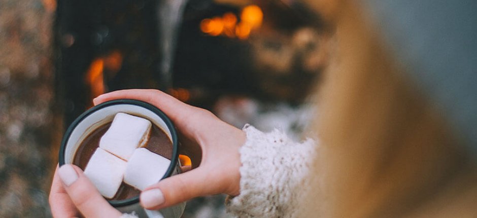 Mädchen trinkt Kakao am Feuer