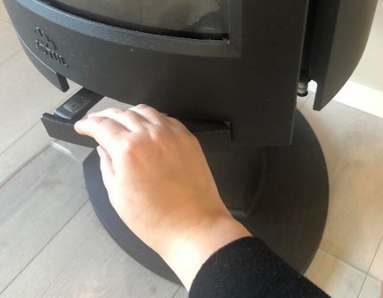 Hand, die vorsichtig die Kamintür des Holzofens Jøtul F 373 Advance öffnet 