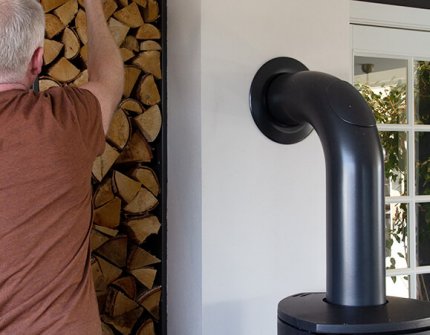 Mann, der das Holz nimmt, um es in den Kamin zu legen