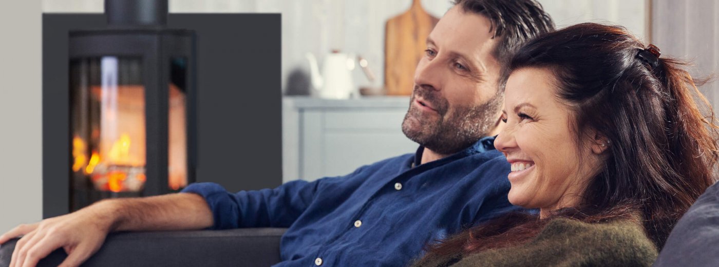 Mann und Frau sitzen vor dem Holzofen Jøtul F 373 Advance im Wohnzimmer 