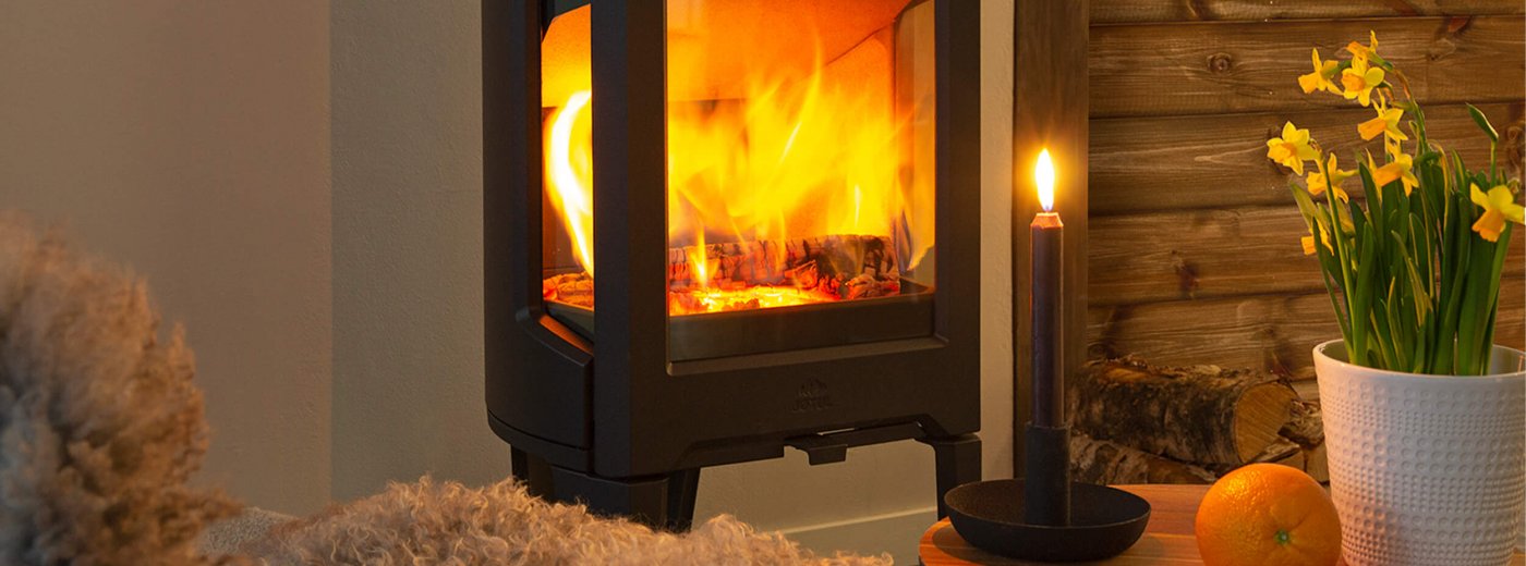 Jøtul F 163 schwarzer Holzofen mit Narzissen in einer Kabine