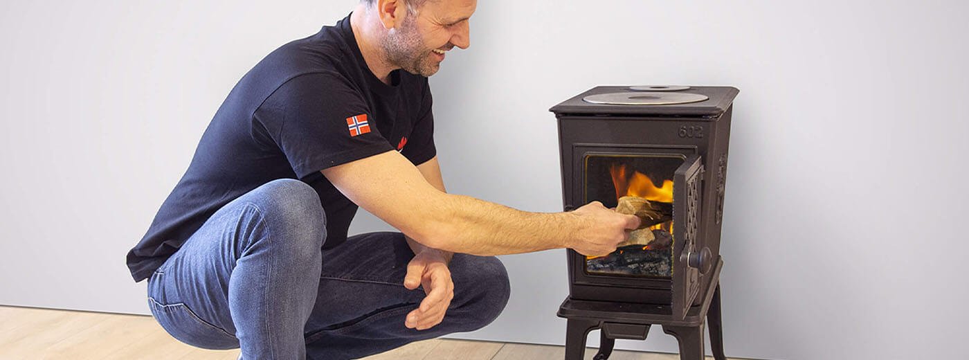 Mann legt Holz in den Holzofen Jøtul F 602