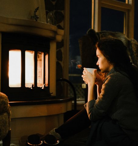 Dame, die abends vor dem Kamin sitzt